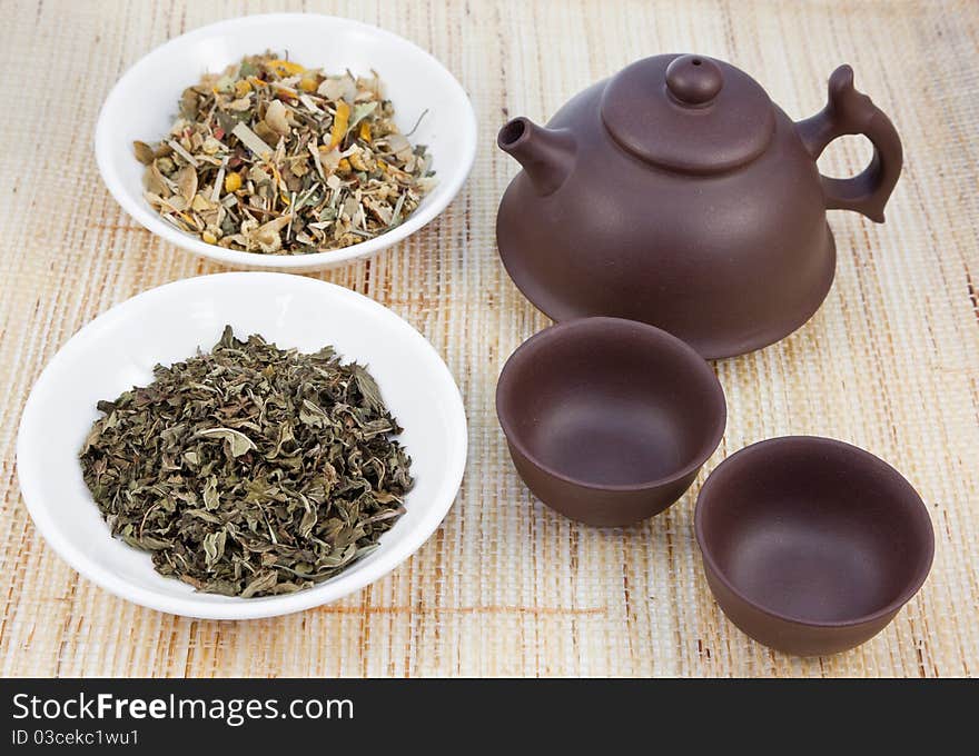 Chinese tea set with herbal teas on natural matting. Chinese tea set with herbal teas on natural matting.