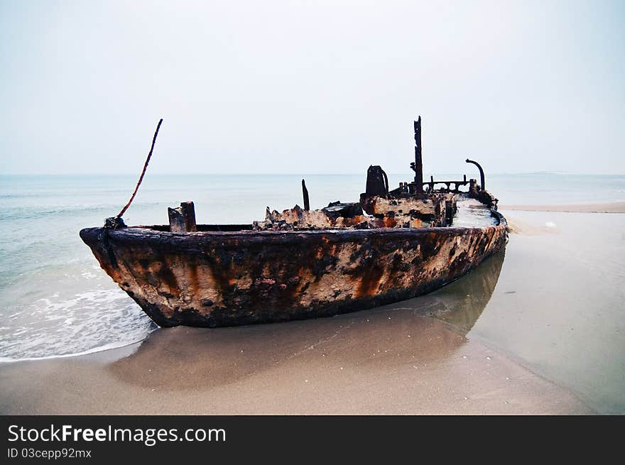 An old rusty ship thrown on a deserted beach. An old rusty ship thrown on a deserted beach