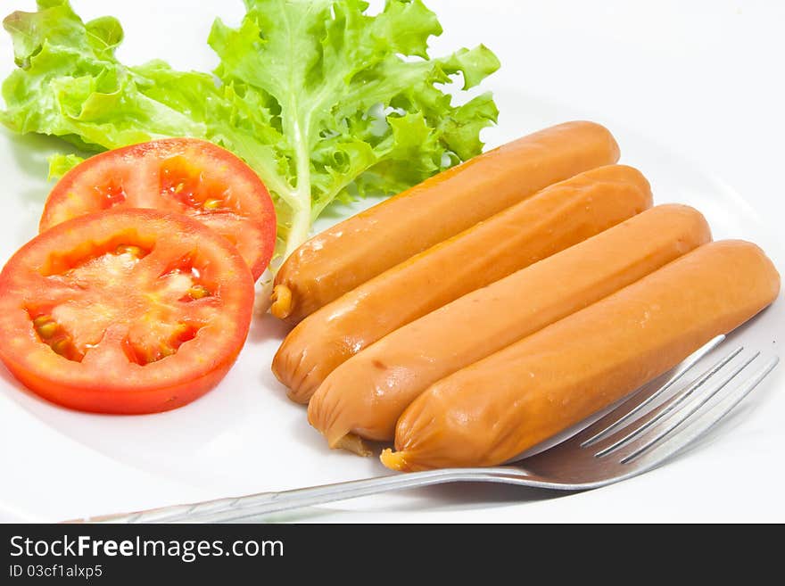 Sausages with fork in the white dish