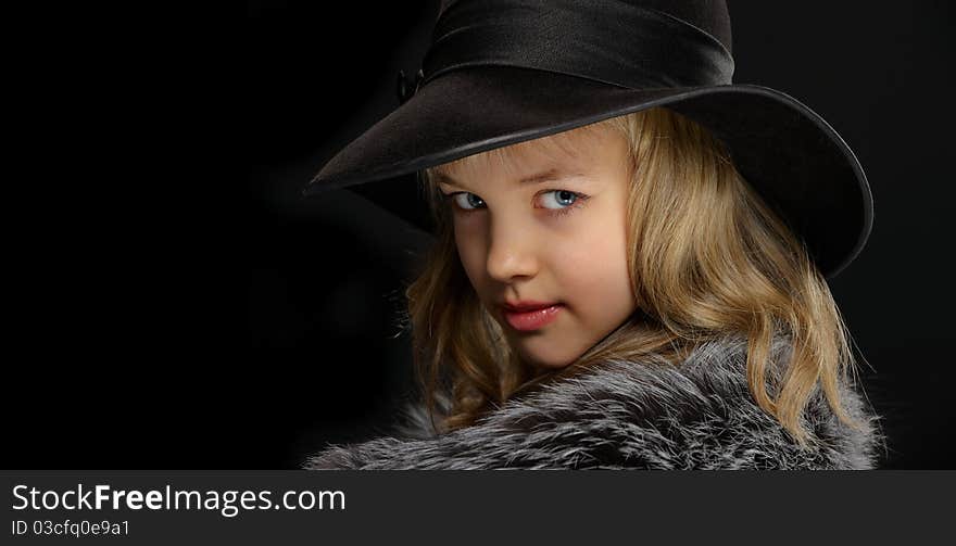 Portrait of a beautiful young lady in gray fur coat and black hat on a black background. Portrait of a beautiful young lady in gray fur coat and black hat on a black background