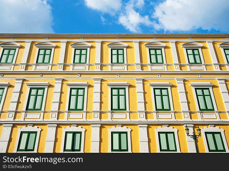 Building office is painted with green windows and yellow wall with design.