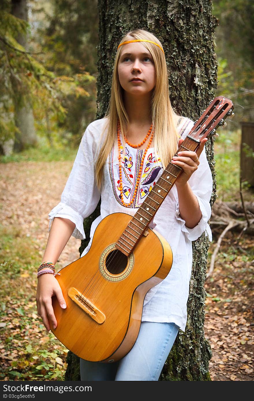 Pretty girl playing guitar and relaxing in the park