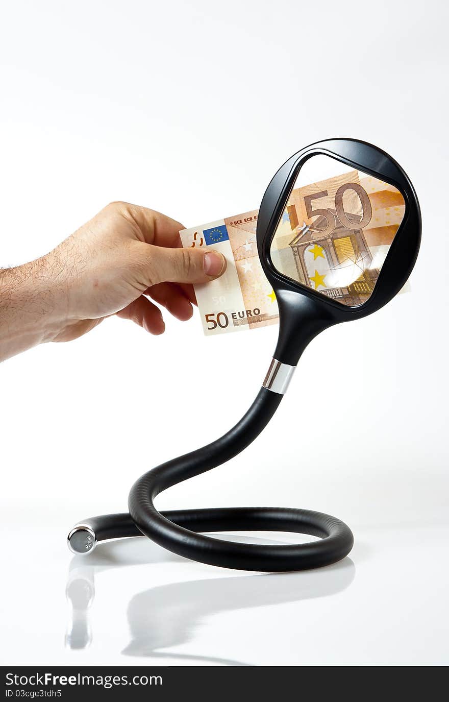 A hand displays a fifty euros through magnifying lens. A hand displays a fifty euros through magnifying lens.