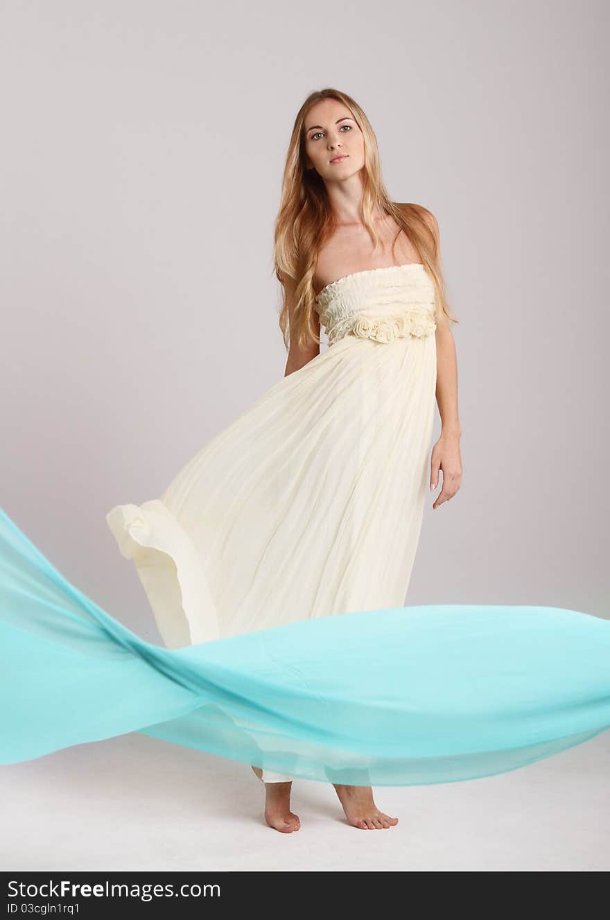 Young fashionable blond girl in long dress. Studio