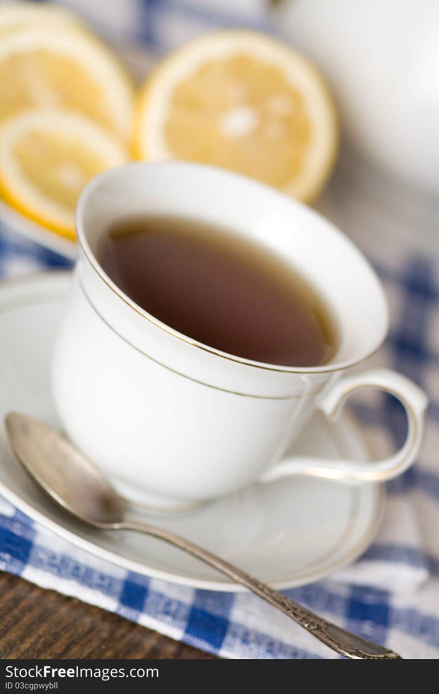 Cup of tea with lemon on blue-white napkin