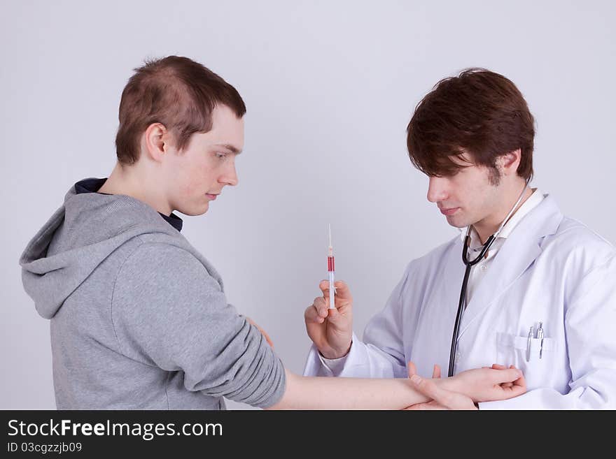 A young man gets an injection from a doctor. A young man gets an injection from a doctor