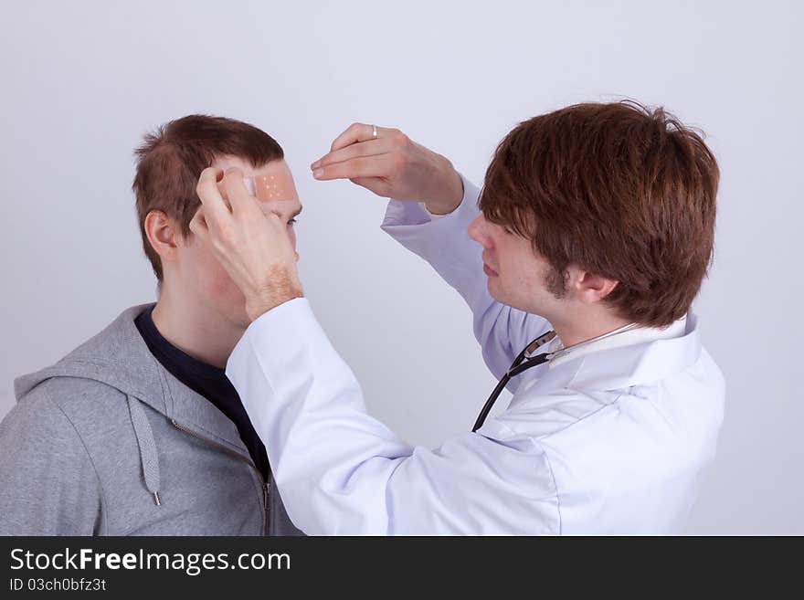 A young man gets a band-aid from his doctor. A young man gets a band-aid from his doctor