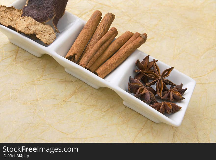 Dried star anise, cinnamon sticks and tangerine peel - herbs and spices in white ceramic dish. Dried star anise, cinnamon sticks and tangerine peel - herbs and spices in white ceramic dish.