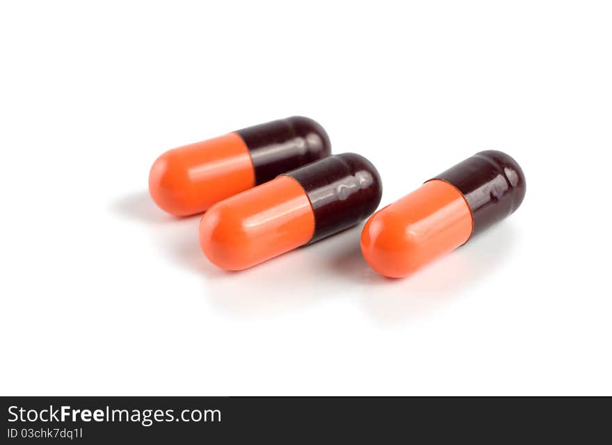 A orange/black capsuled isolated on a white background. A orange/black capsuled isolated on a white background