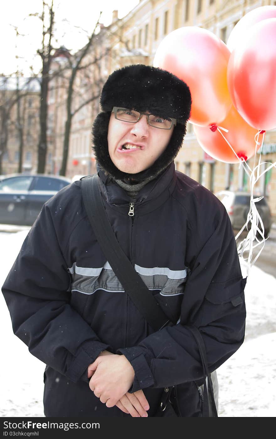 Happy boy in a stylish cap earflaps with pink and red balloons. Happy boy in a stylish cap earflaps with pink and red balloons