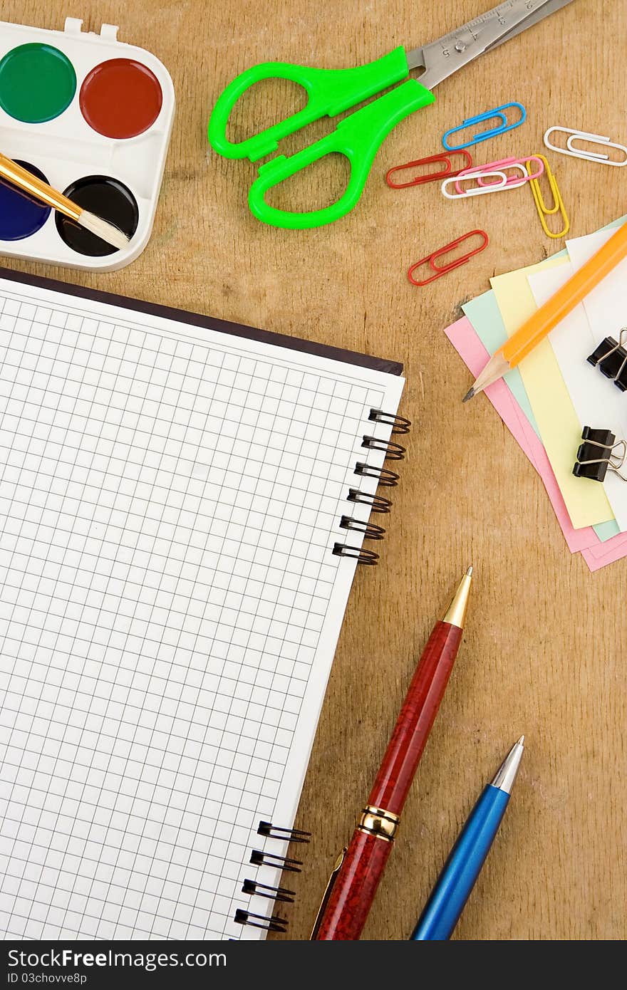 School accessories and checked notebook on wooden table