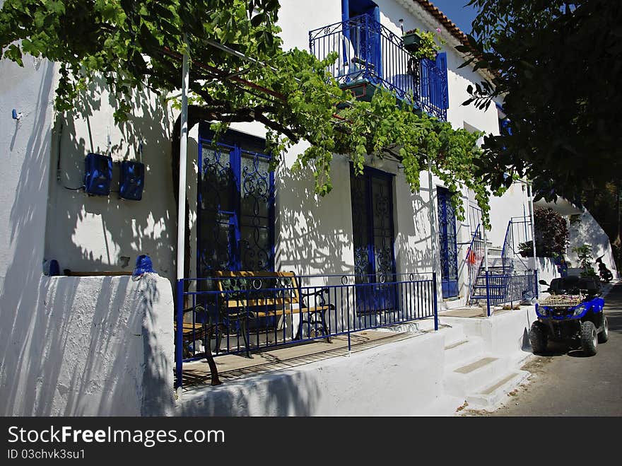 Traditional greek house painted in white with blue details at sunny summer day. Traditional greek house painted in white with blue details at sunny summer day.