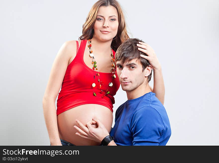 Handsome man showing ok sign on his wife's pregnant belly