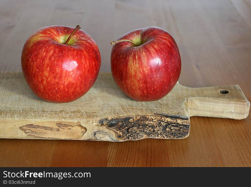 Two apples on wooden chopping board