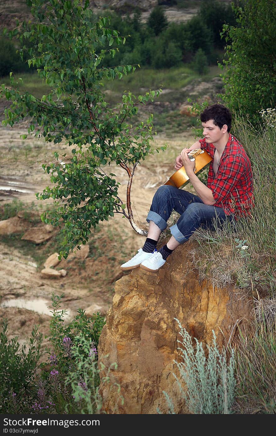 A lone young man with a guitar against breakage. A lone young man with a guitar against breakage