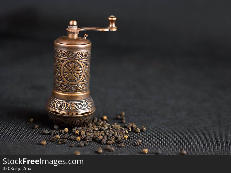 Vintage still life with brass pepper mil standing on the grey background