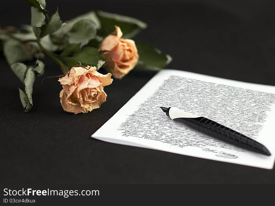 Beautiful dry roses on the black background end letter