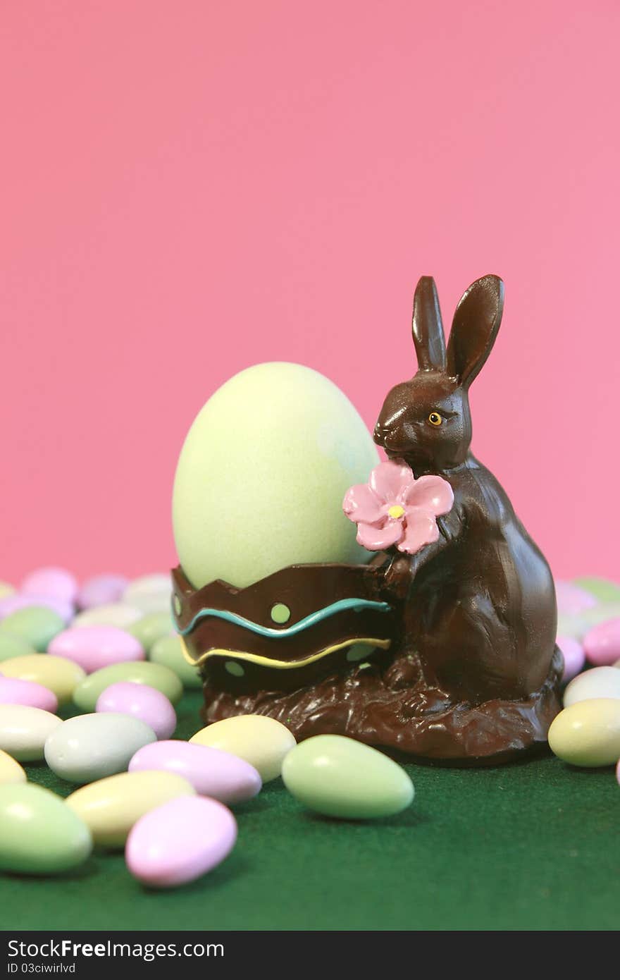 Chocolate Easter bunny holding egg with pastel candy