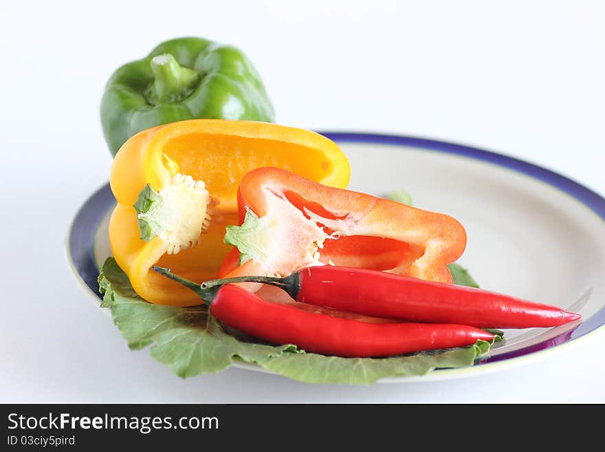 Hot and spicy salad containing red chillies and green, yellow and red capsicum on white background