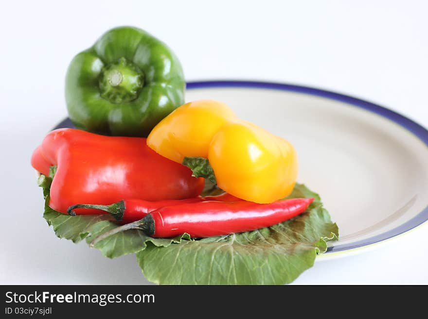 Hot and spicy salad containing red chillies and green, yellow and red capsicum on white background