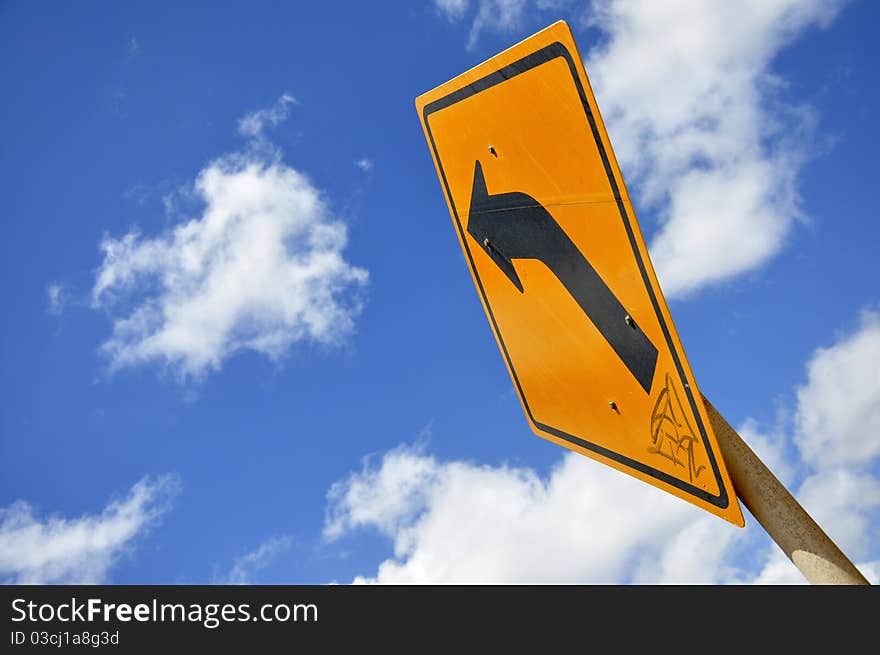 Curved Road Traffic Sign under the blue sky with clouds