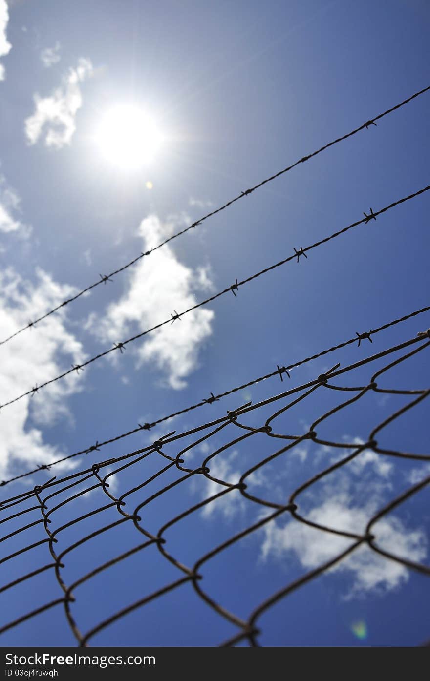 Fence with barbed wire under blue sky