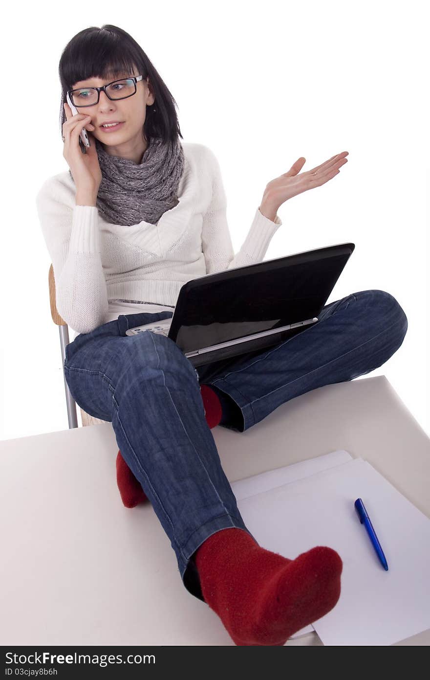 Brunette woman sits thrown feet on the desk and talking on the phone on white background. Brunette woman sits thrown feet on the desk and talking on the phone on white background