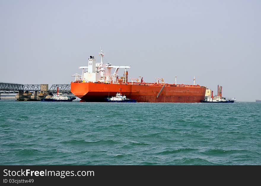 A huge oil tanker and tugboats at work. A huge oil tanker and tugboats at work