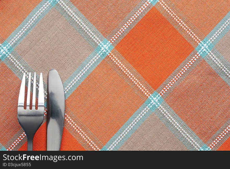 Fork and table knife lying on chequered tablecloth. Fork and table knife lying on chequered tablecloth