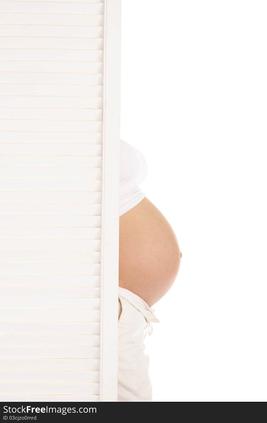 Belly pregnant woman leaned out from behind the door isolated on white