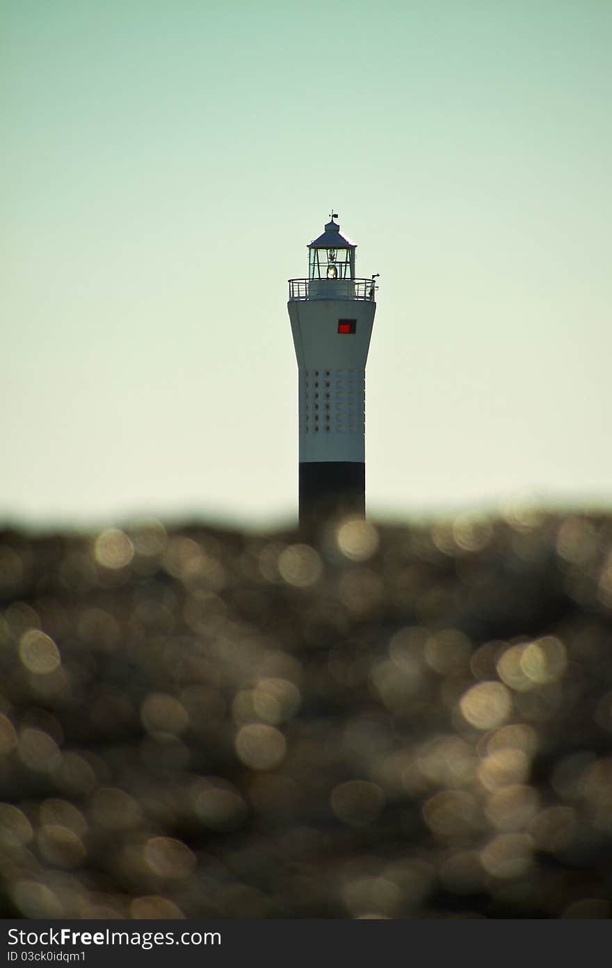 Dungeness lighthouse shot from low on the beach with the shingle reflecting in the sunshine. Dungeness lighthouse shot from low on the beach with the shingle reflecting in the sunshine