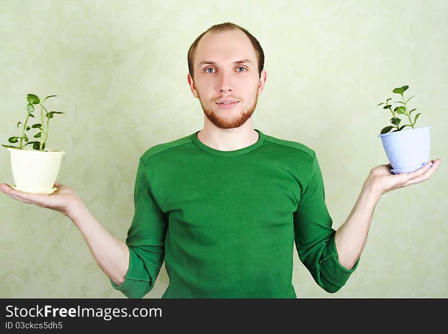 Man in green shirt holding two flowerpots with Kalanchoe plants. Man in green shirt holding two flowerpots with Kalanchoe plants