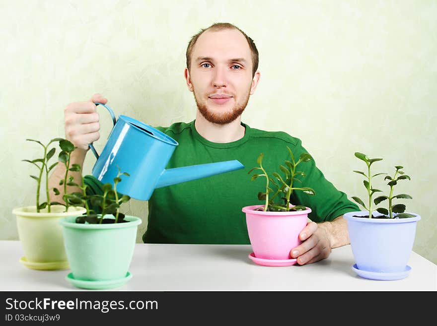 Man Sitting Near Table And Watering Plants