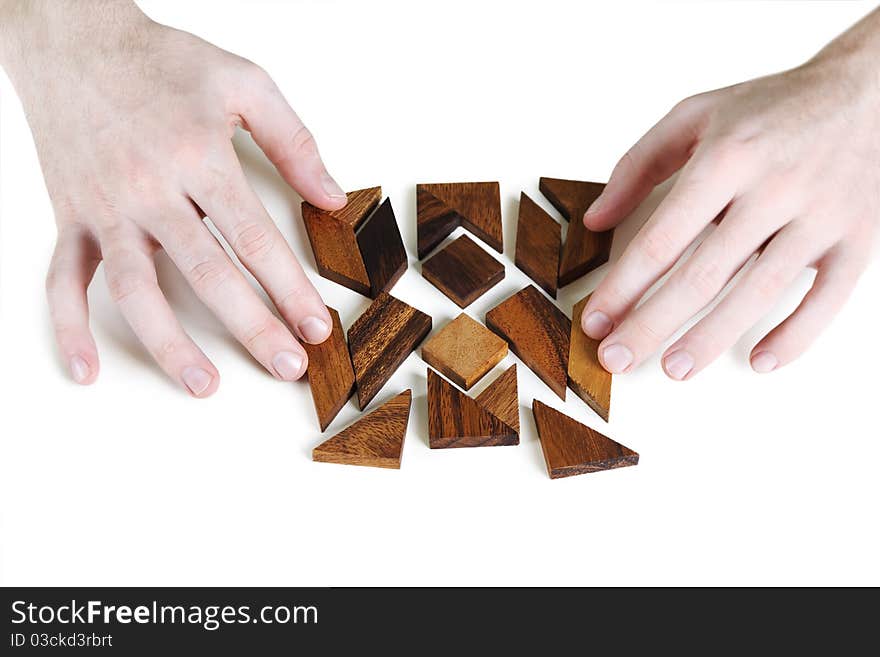 Closeup of mans hands assembling wooden square puzzle, isolated