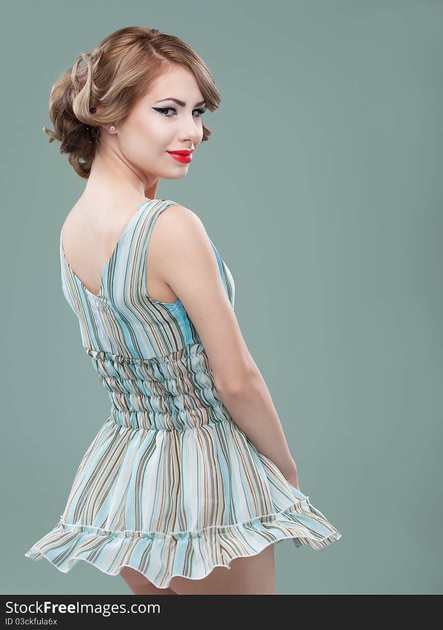 Studio portrait of a young, blonde woman, wearing a blue mini dress, twirling in it and smiling to the camera. Studio portrait of a young, blonde woman, wearing a blue mini dress, twirling in it and smiling to the camera.