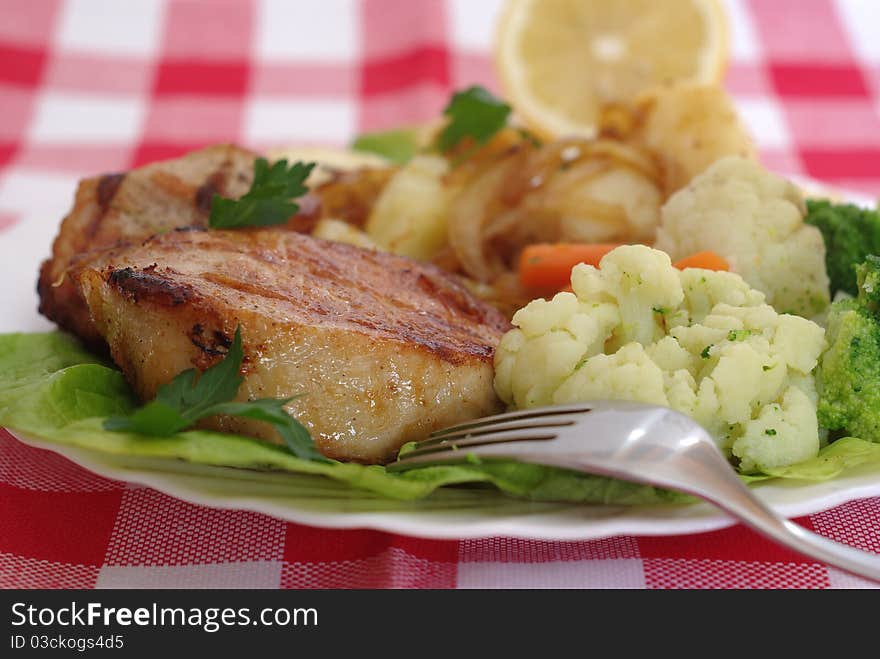 Meat from grill with vegetables on plate