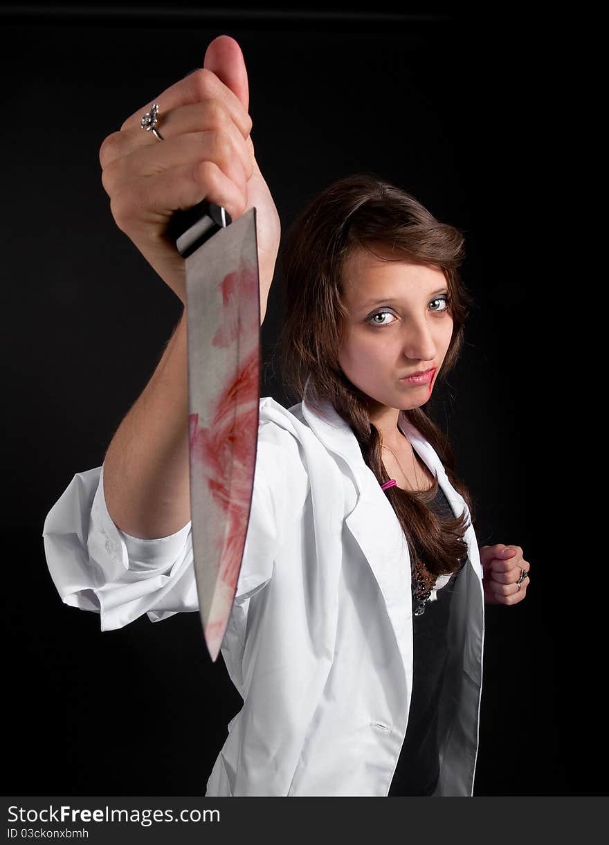 Mad nurse holds a bloody knife in the dark