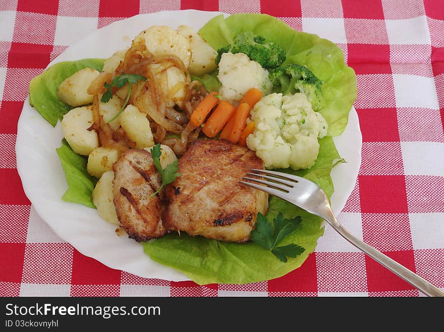 Meat from grill with vegetables on plate