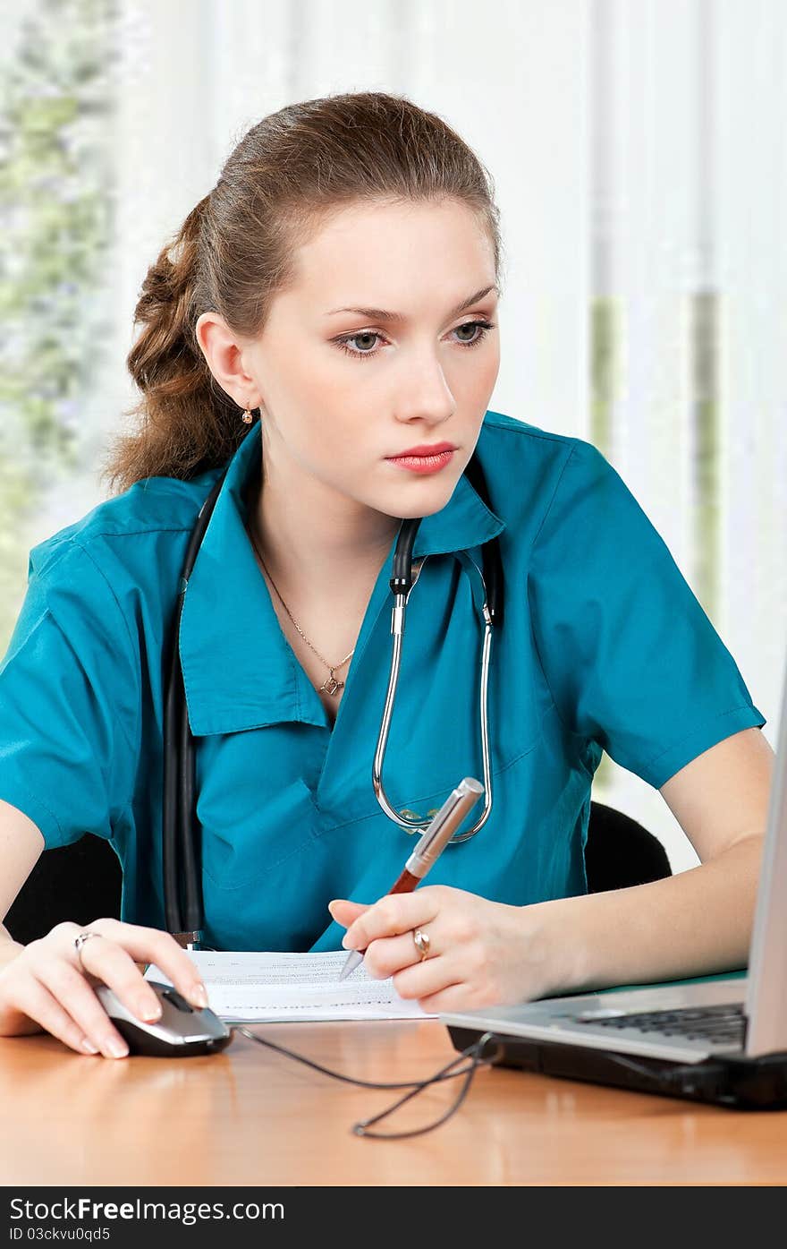 Beautiful young doctor working with laptop at her office. Beautiful young doctor working with laptop at her office