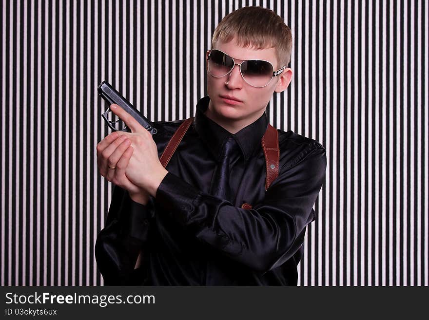 Serious man with a gun standing against striped background