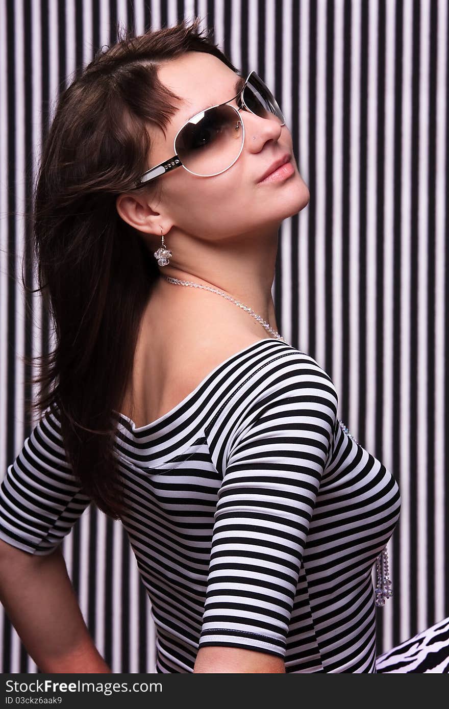 Cute girl in a striped clothes and sunglasses on the striped background