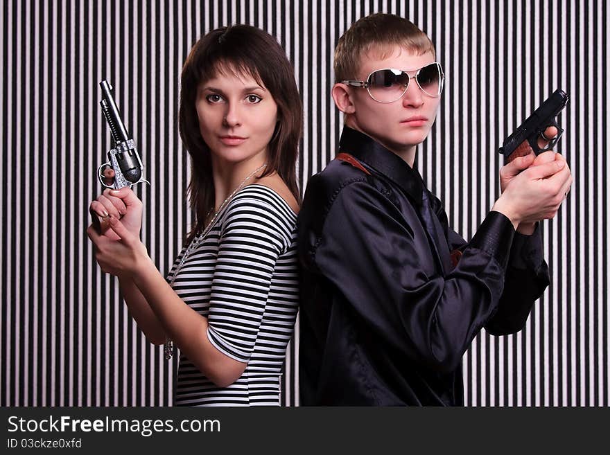 Young couple holding guns over stripe background