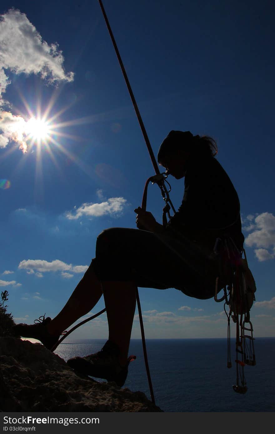 Adrenaline sport - silhouette of a climber above the sea. Adrenaline sport - silhouette of a climber above the sea