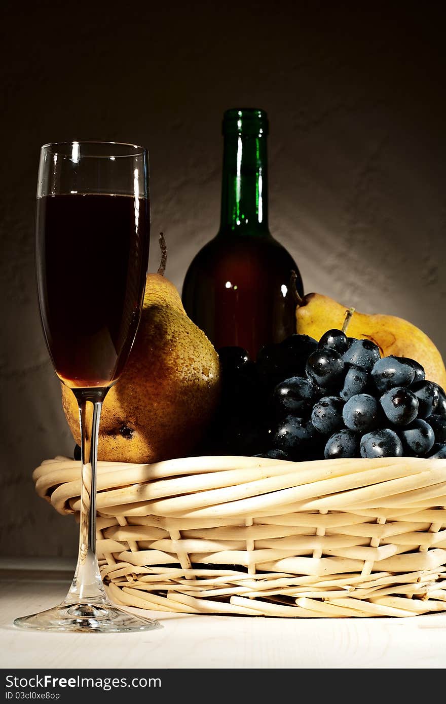 Still life with red wine and fruits on the desk