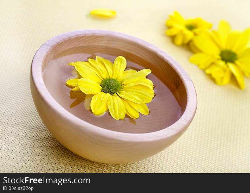 Yellow flowers in wooden bowl. Spa theme