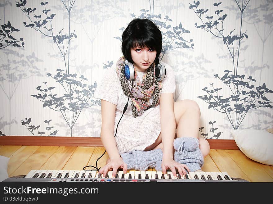 Cute young woman with headphones playing on piano, studio shot. Cute young woman with headphones playing on piano, studio shot