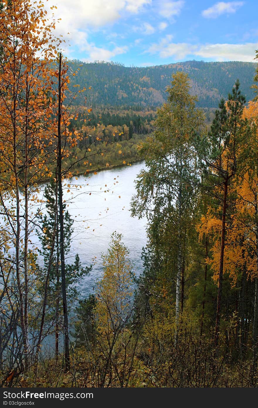 Autumn landscape with river, mountains and multi-colored forest.