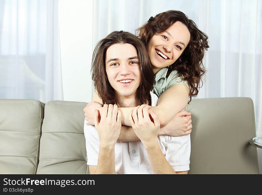 Loving young couple with arms around and smiling. Indoors. Loving young couple with arms around and smiling. Indoors