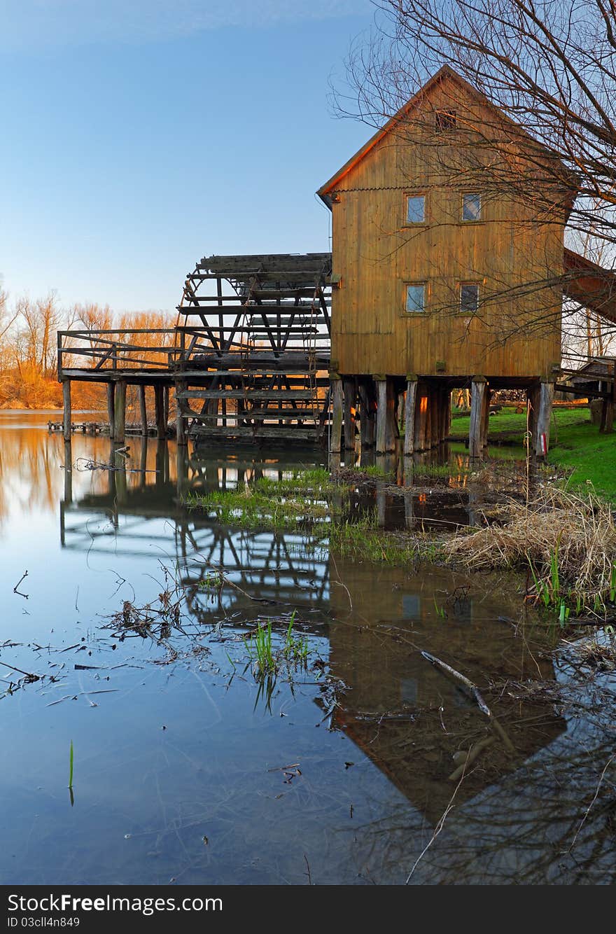 Historic wooden watermill with reflection.