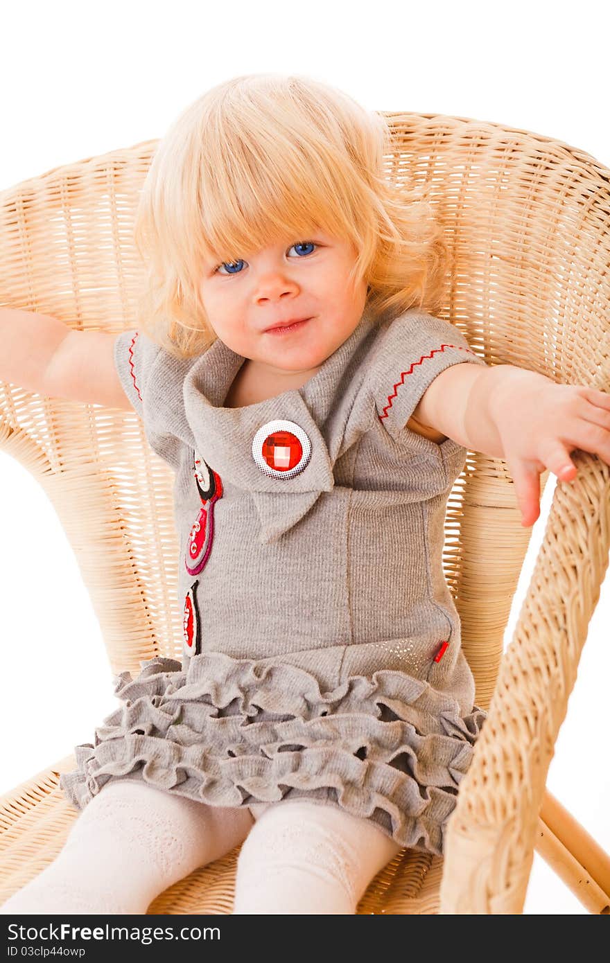 Pretty little girl sitting on wicker amchair